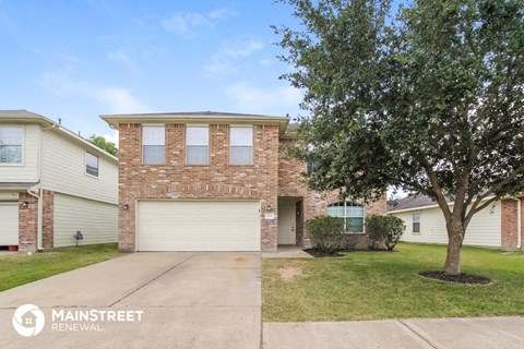 a brick house with a white garage door and a tree