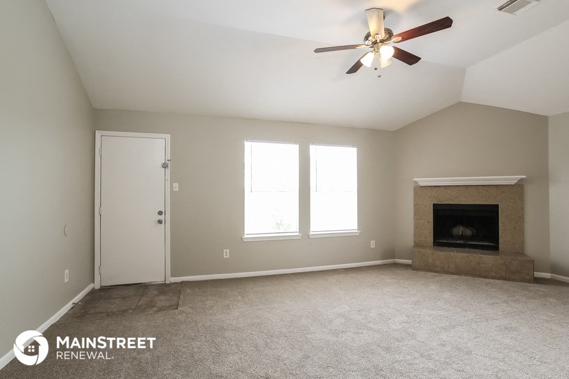 the spacious living room with fireplace and ceiling fan