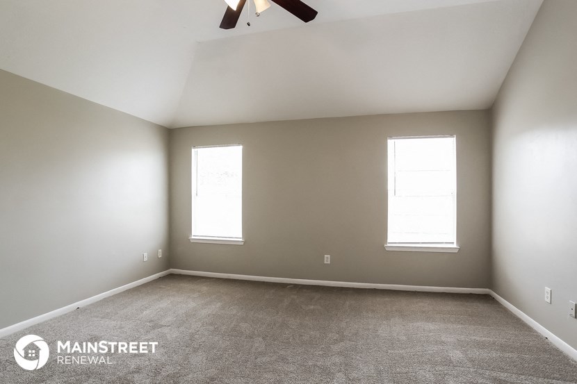 an empty room with a ceiling fan and two windows