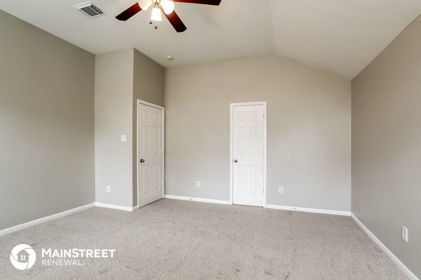 the master bedroom has a carpeted floor and a ceiling fan