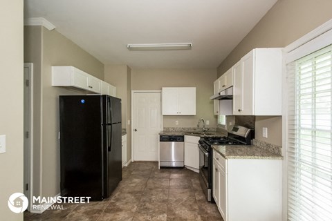 a kitchen with white cabinets and a black refrigerator