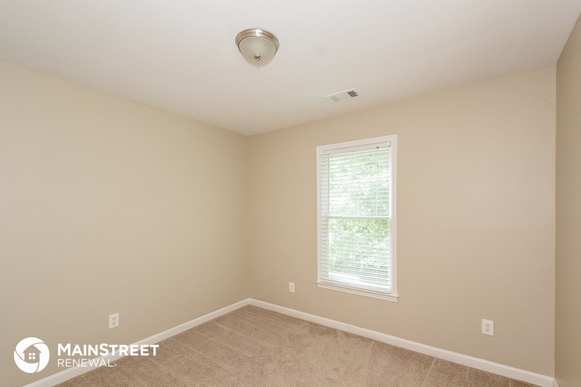 the upstairs bedroom has a carpeted floor and a large window