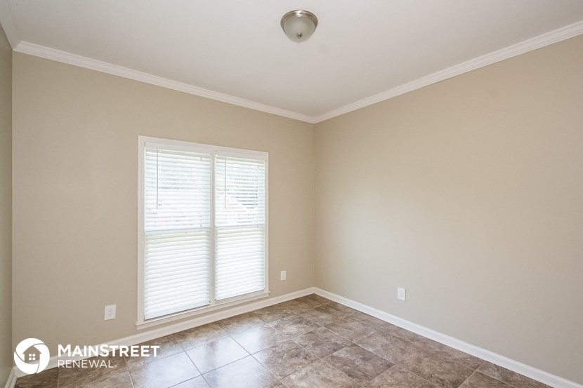 the living room of a house with a large window and a tiled floor