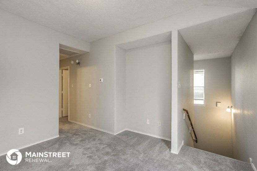 the living room of an apartment with white walls and carpet