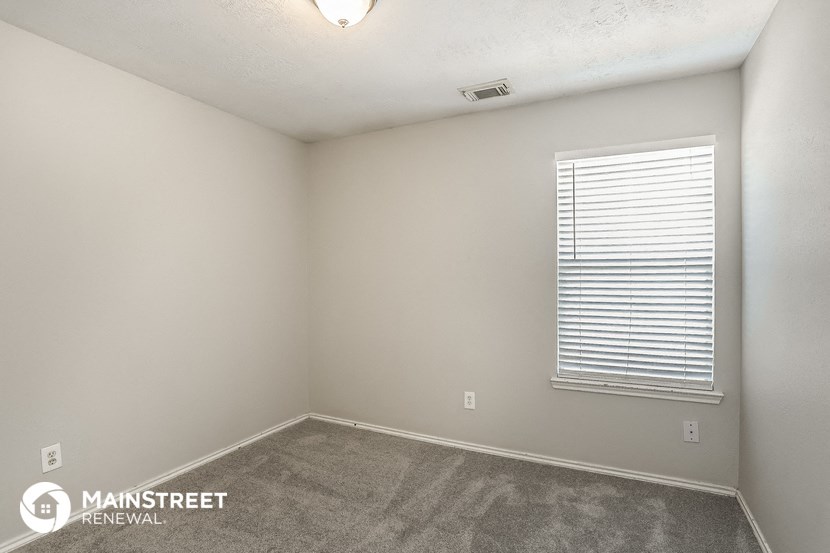 the spacious living room of a manufactured home with carpet and a window
