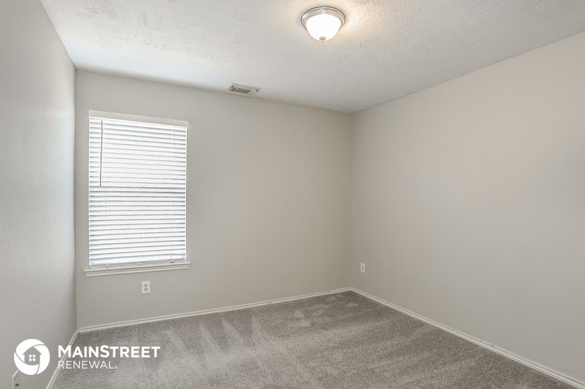 the spacious living room of a house with carpet and a window