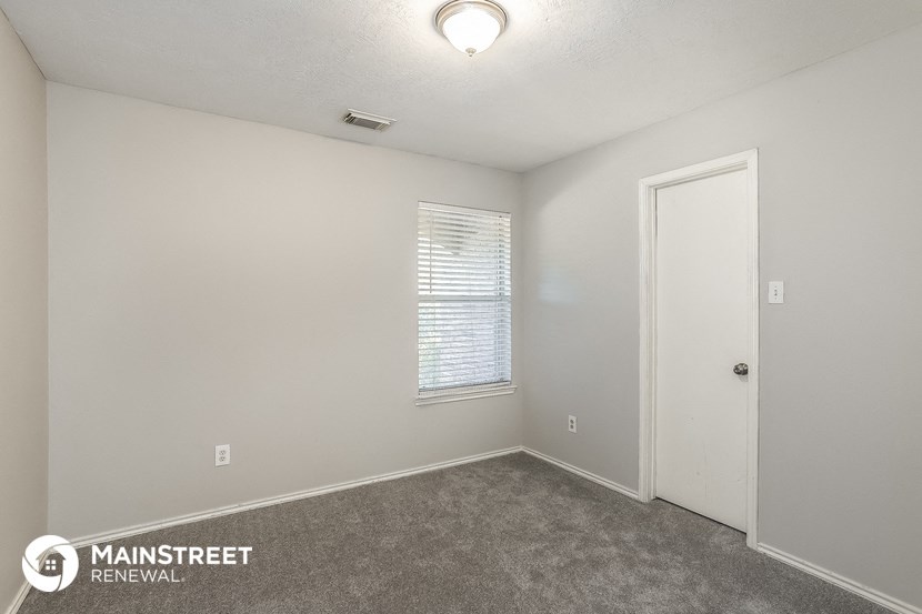the spacious living room of a house with carpet and a door to a closet