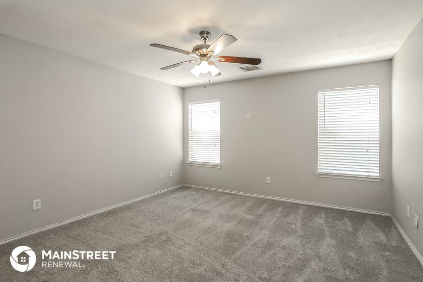 the spacious living room with ceiling fan and carpet