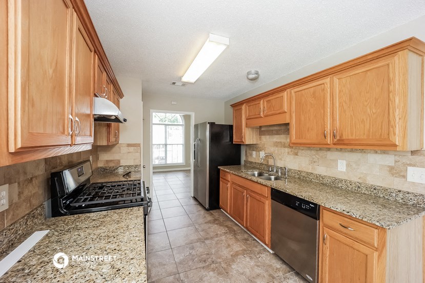 a kitchen with wood cabinets and granite counter tops and a black refrigerator