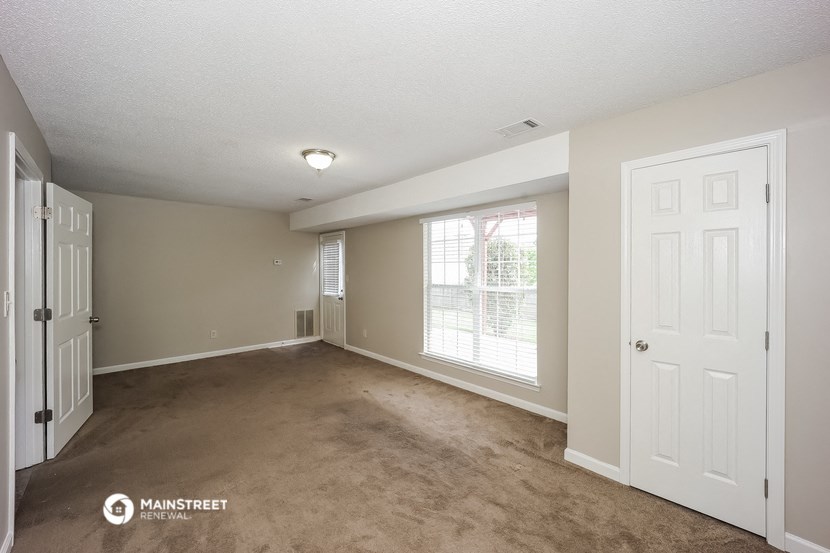 an empty living room with a white door and a window