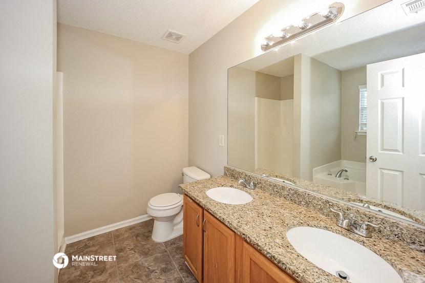 a bathroom with two sinks and a toilet and a mirror