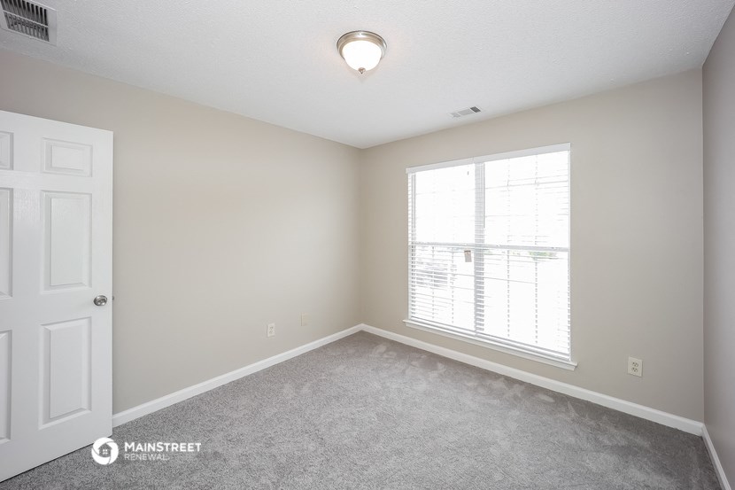an empty room with a large window and a white door