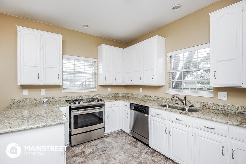 a kitchen with white cabinets and granite counter tops and stainless steel appliances