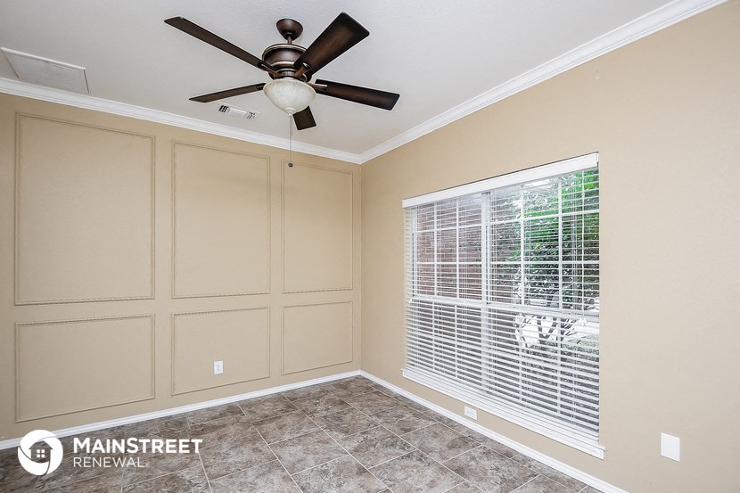the living room has a large window and a ceiling fan