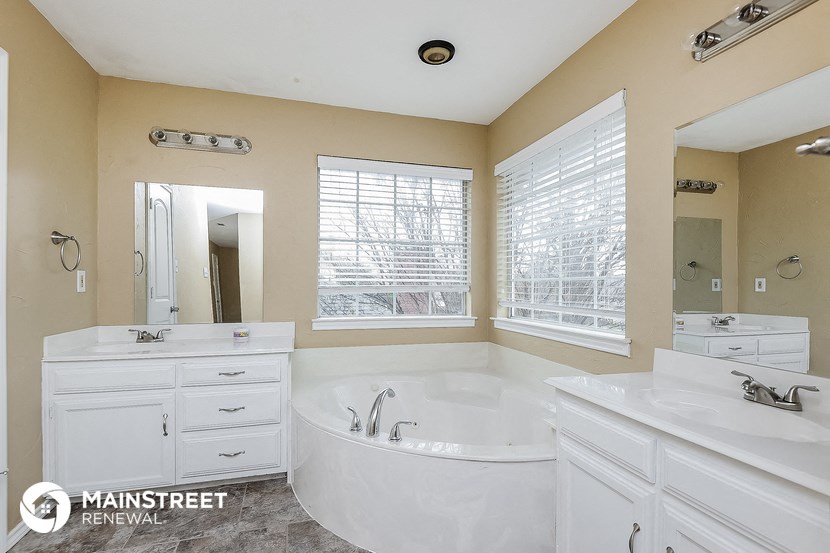 a large white bathroom with a large tub and two sinks