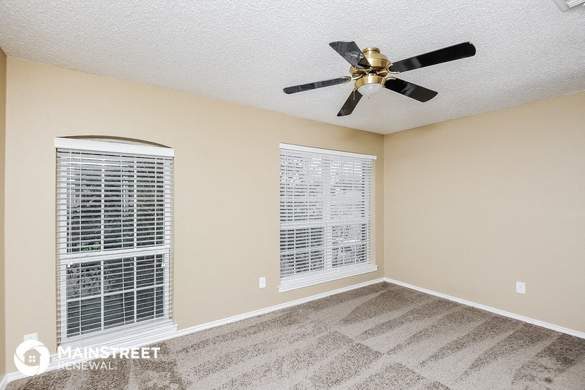 the master bedroom has a ceiling fan and window