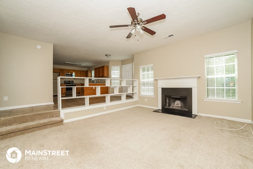 an empty living room with a fireplace and a ceiling fan