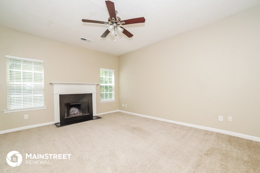 a living room with a fireplace and a ceiling fan