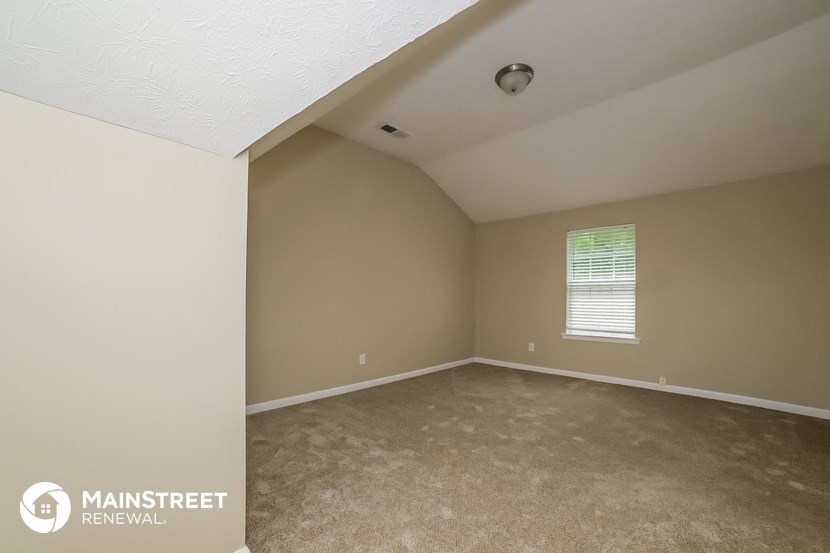 the upstairs bedroom with carpeted flooring and a window