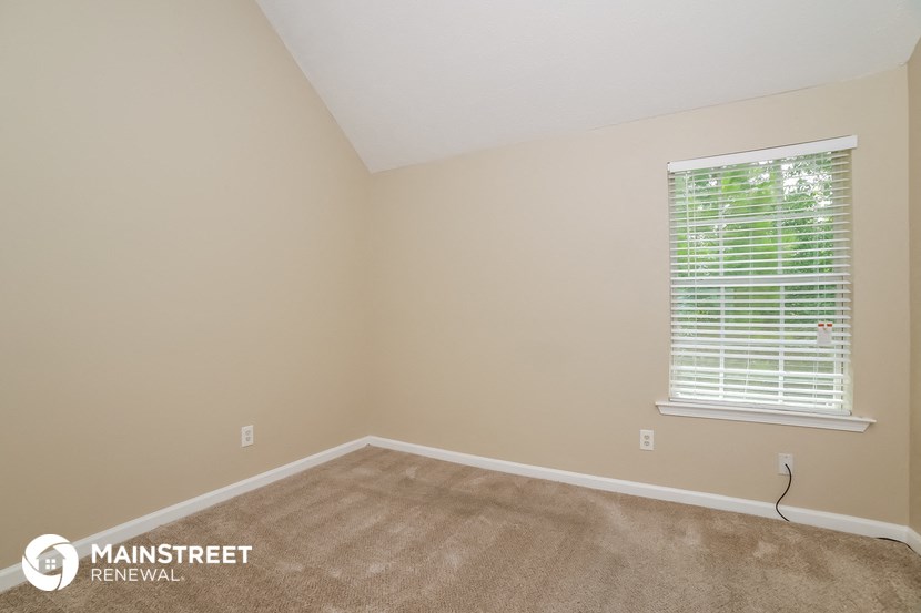 the living room of a home with a large window and carpet