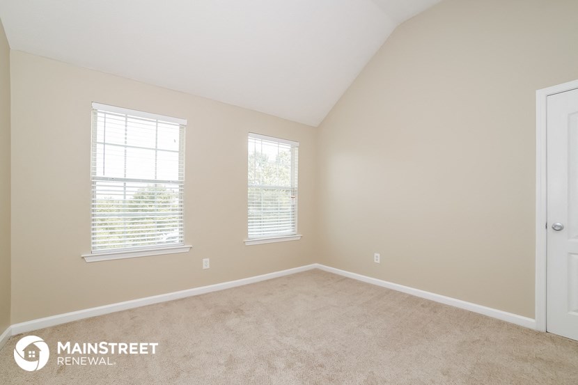a bedroom with a carpeted floor and three windows