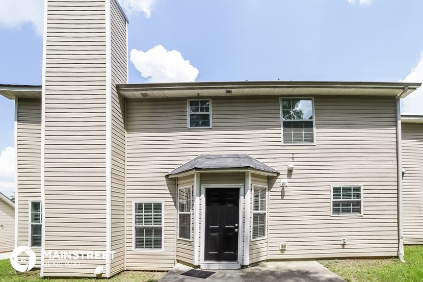 the front of a white house with a black door