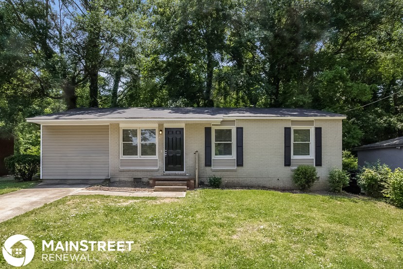 a small tan house with a lawn and trees
