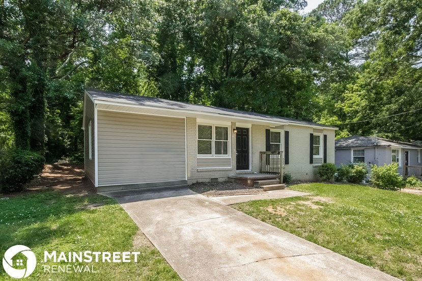 a small white house with a lawn and trees