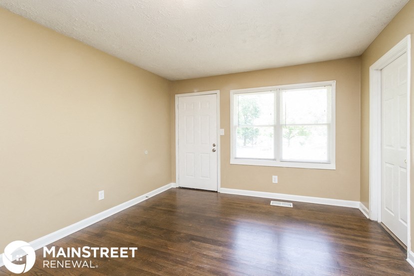 a living room with wood floors and a white door and window