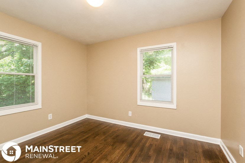 the interior of an empty room with wooden floors and two windows