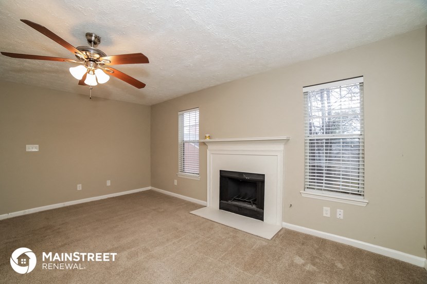 a living room with a fireplace and a ceiling fan
