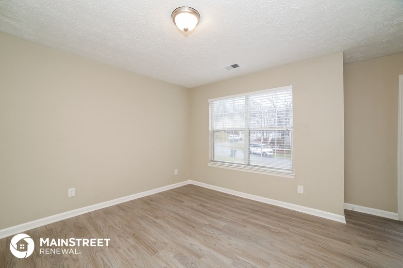 the spacious living room with wood flooring and a large window