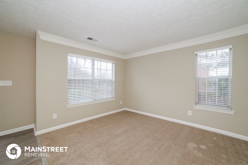 the spacious living room with carpeting and two windows