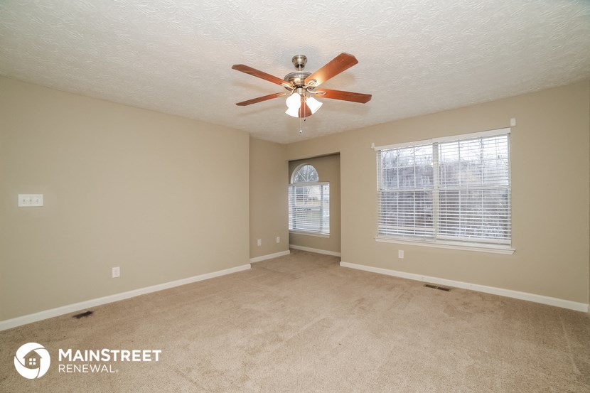 an empty living room with a ceiling fan and a window