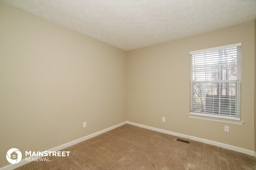 the upstairs bedroom with carpet and a window