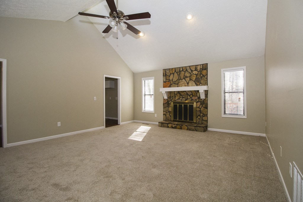 an empty living room with a fireplace and a ceiling fan