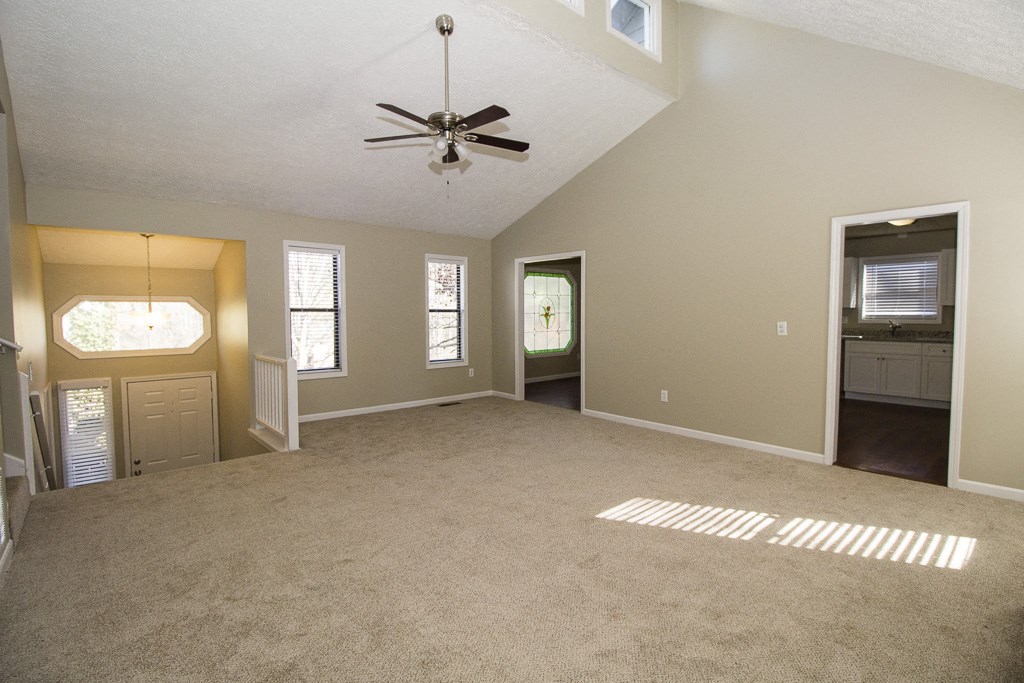 an empty living room with a ceiling fan