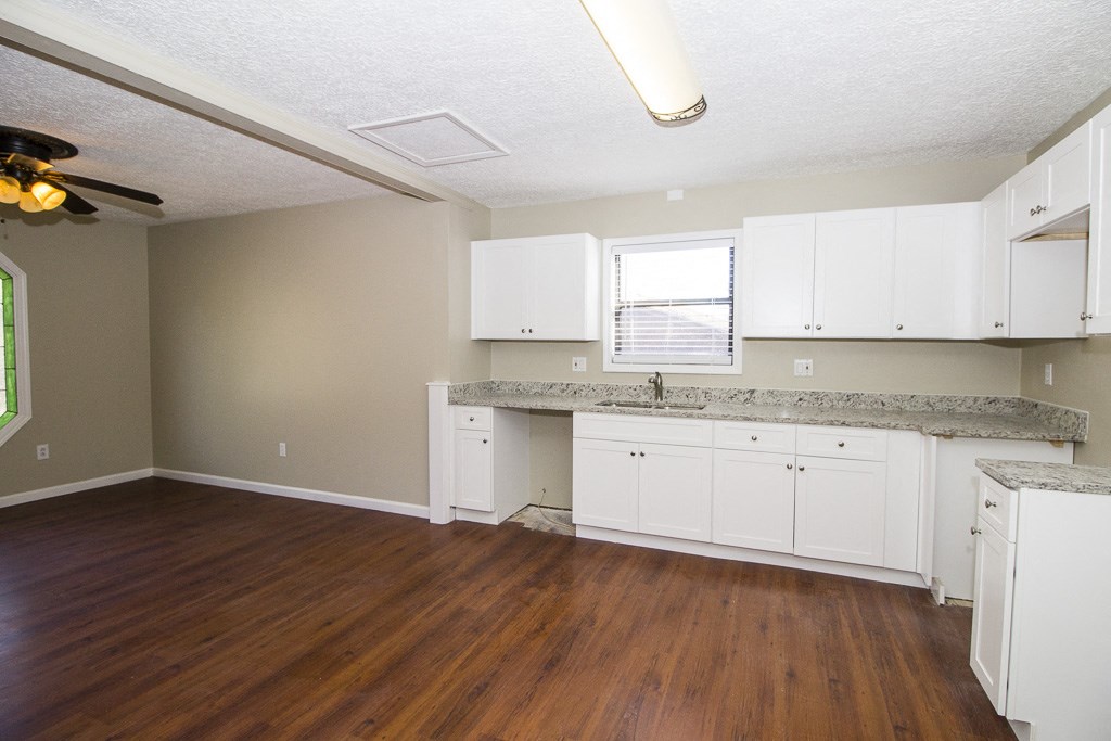 an empty kitchen with white cabinets and a wood floor