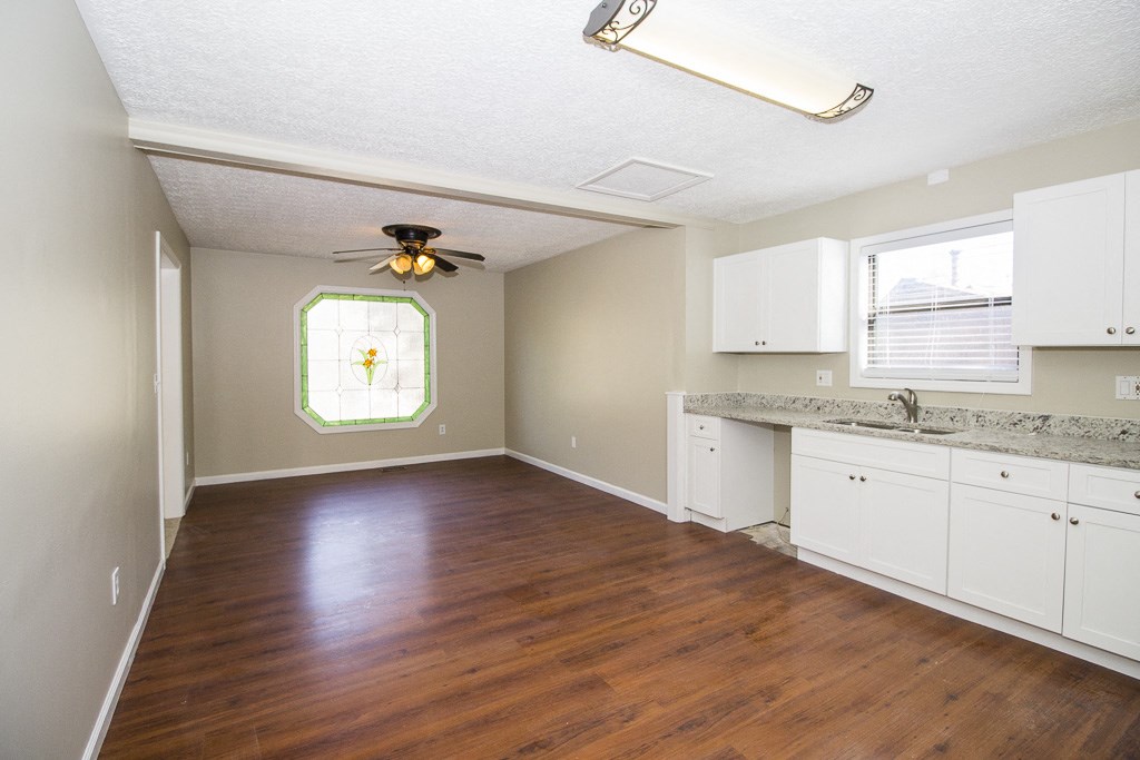 an empty kitchen with white cabinets and a wood floor