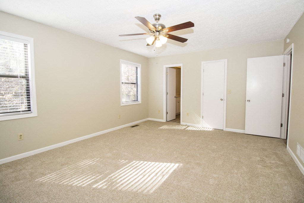 an empty living room with a ceiling fan