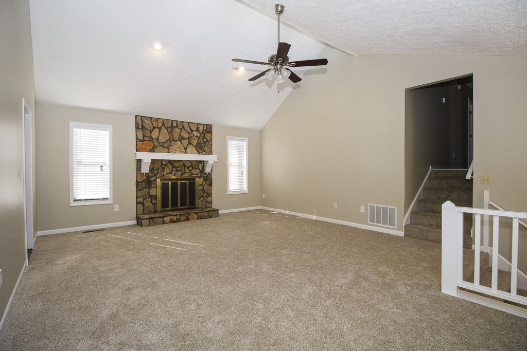 an empty living room with a fireplace and a ceiling fan