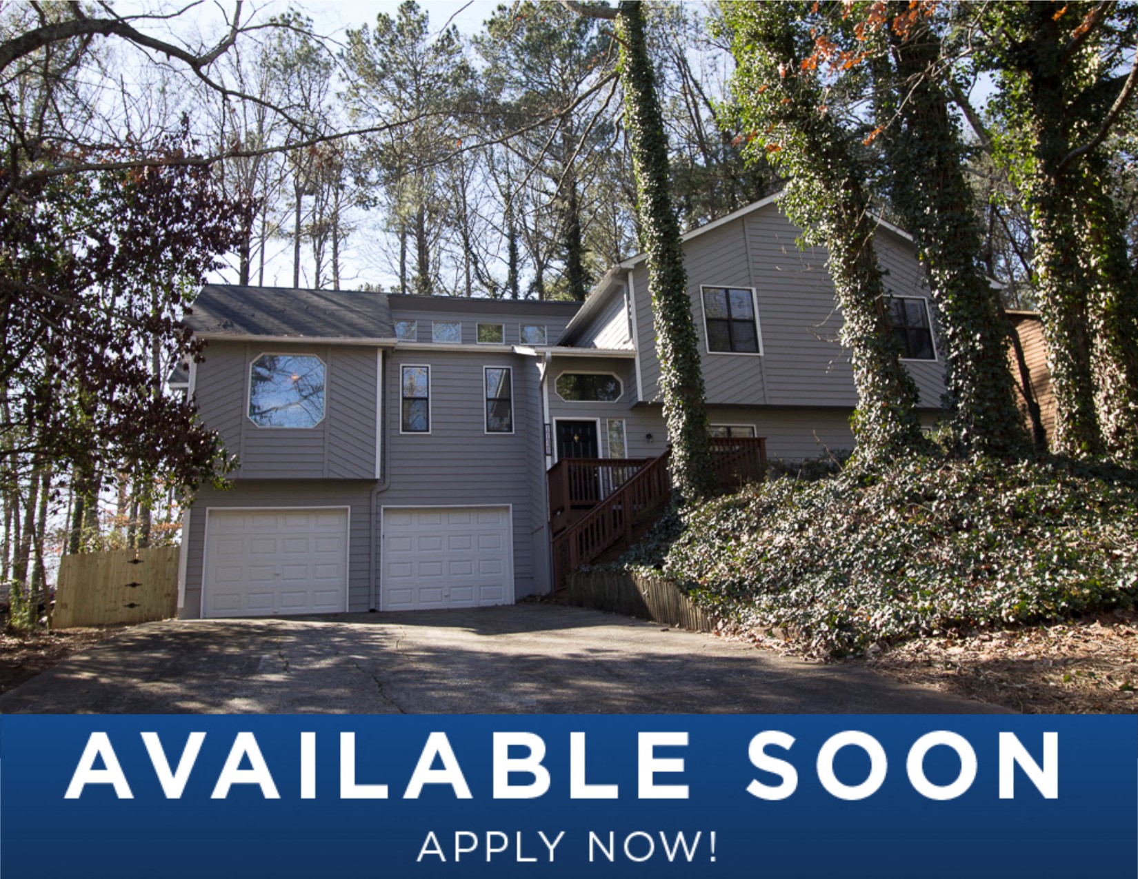 a gray house with a driveway and trees