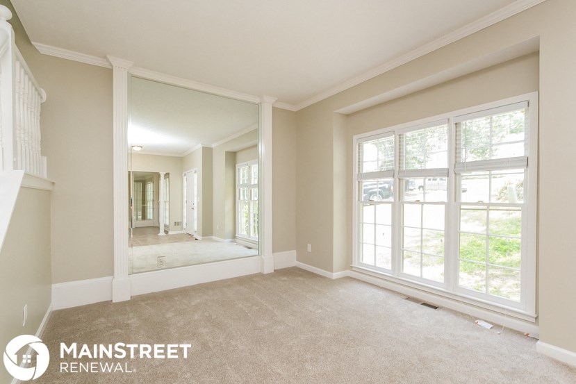 an empty living room with large windows and a mirror
