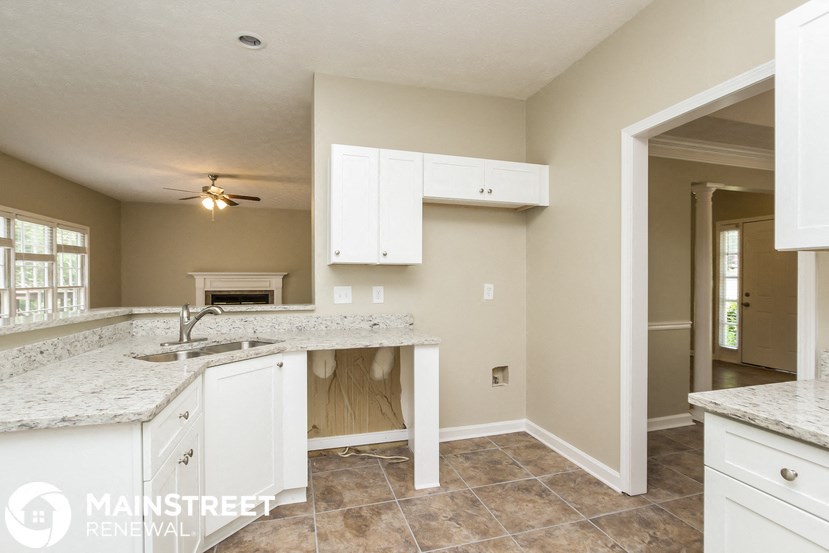 a kitchen with white cabinets and granite counter tops and a sink