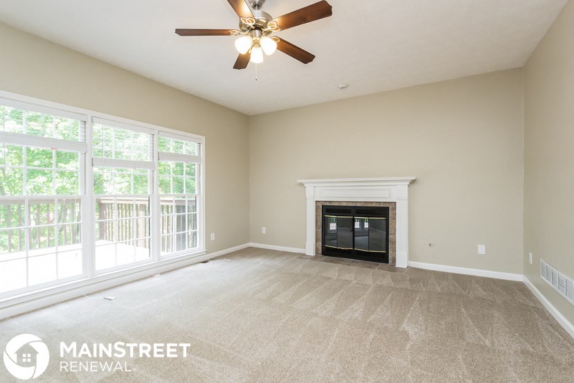 an empty living room with a fireplace and a ceiling fan