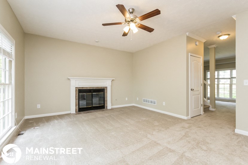 an empty living room with a fireplace and a ceiling fan