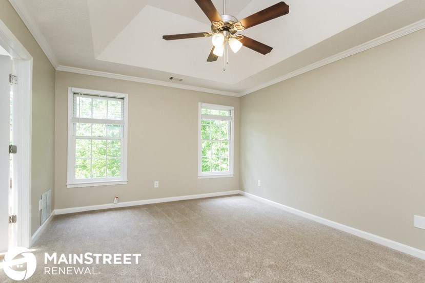 an empty living room with a ceiling fan and two windows
