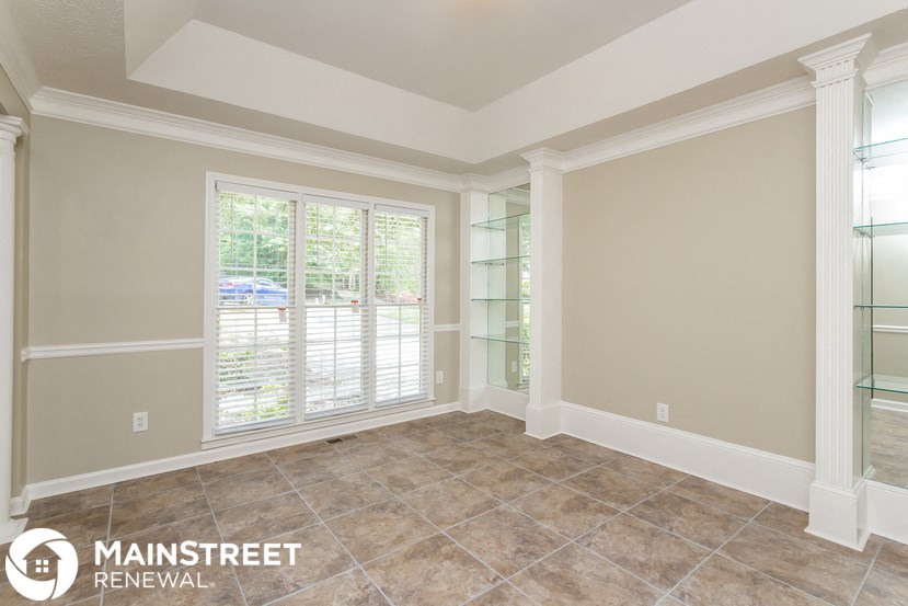 the living room of a home with a large window and tiled floors