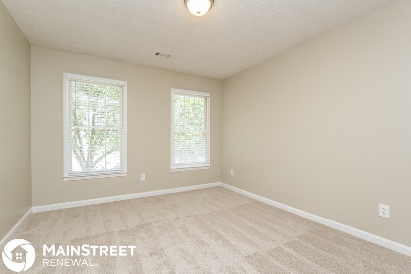 the upstairs bedroom with carpeted flooring and two windows