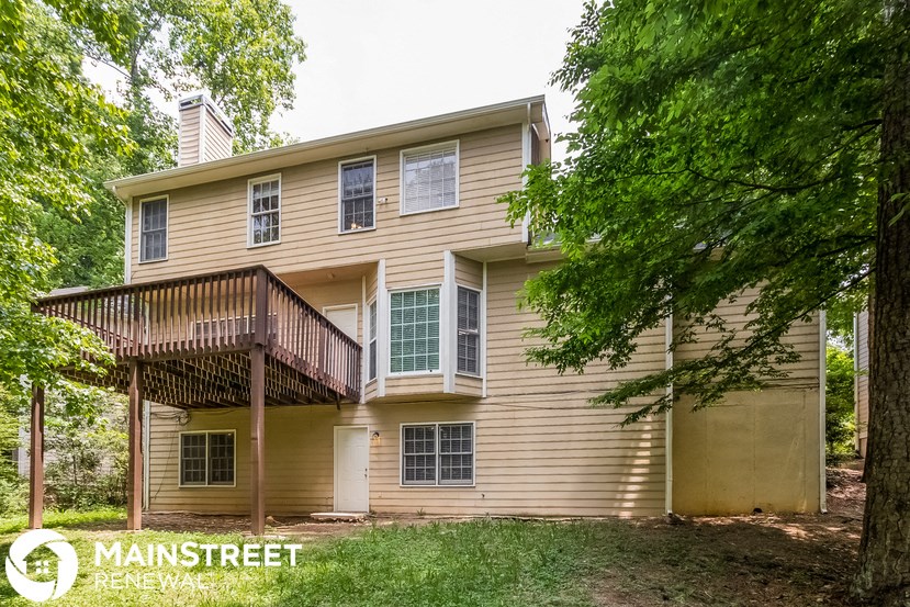 a yellow house with a deck and a tree